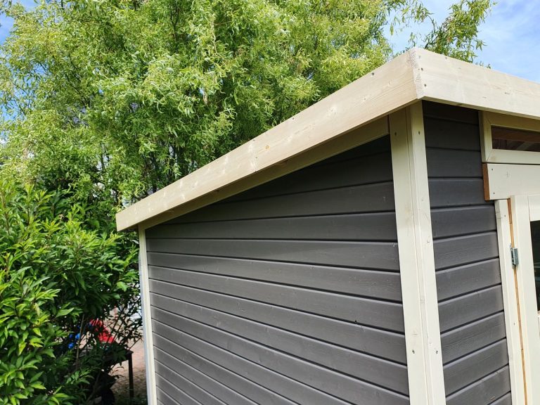 Ecke eines Gartenhauses mit anthrazitfarbener Verschalung und weißen Kantenprofilen