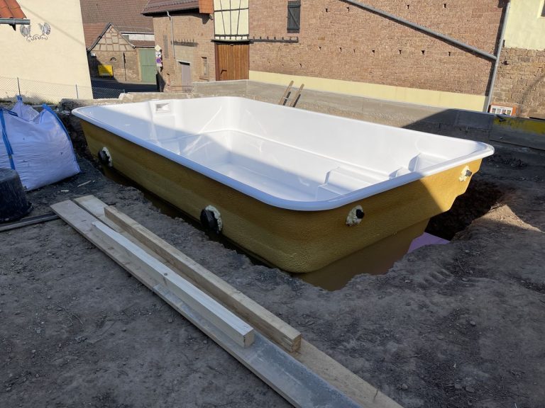GFK-Poolbecken auf der Baustelle abgestellt, vorbereitet zum Einsetzen
