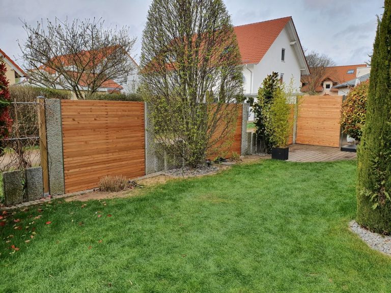 Sichtschutzzaun aus Holz entlang der Gartengrenze mit angrenzender Rasenfläche