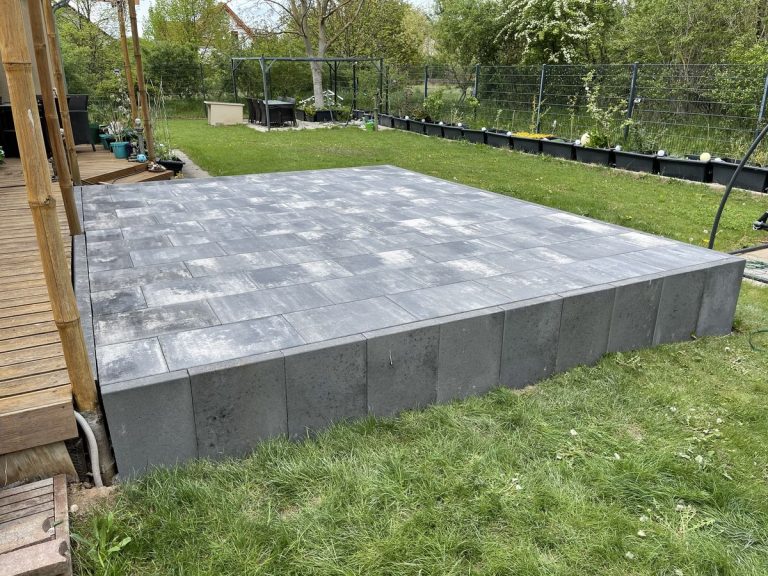 Erhöhte Plattenterrasse aus Betonwerkstein mit sauberer Kante zur Rasenfläche