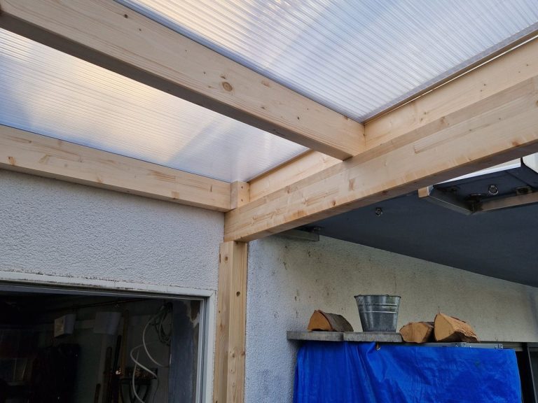 Pfosten einer Terrassenüberdachung aus Holz im Anschluss an die Hauswand